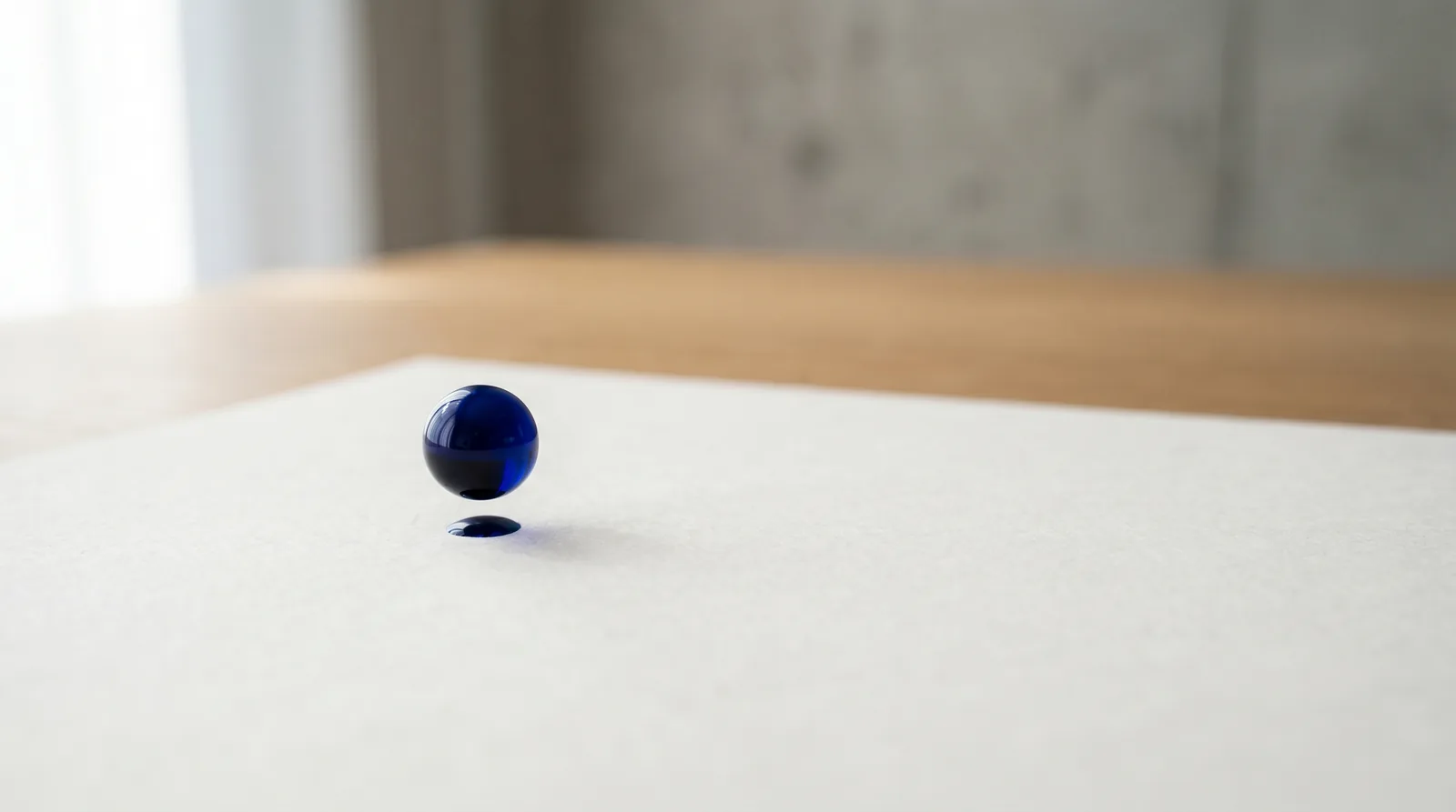 Goutte d'encre bleue suspendue au-dessus d'une feuille blanche, métaphore visuelle du refresh discipliné Doctolib