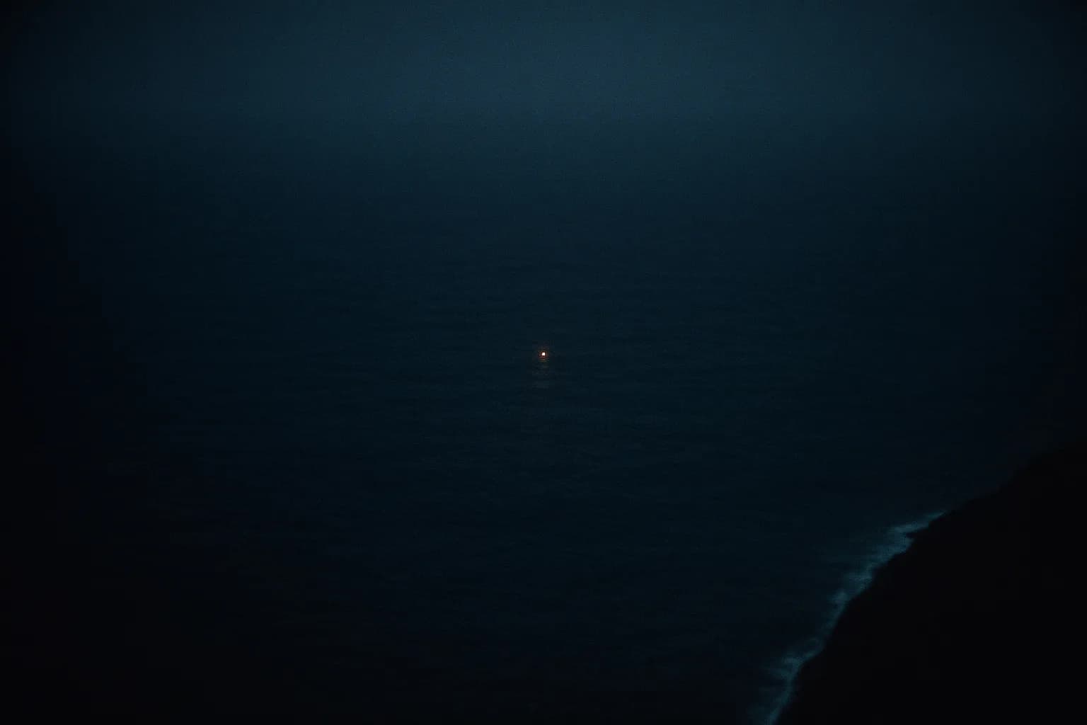 Vue satellite sombre d'un océan de nuit presque entièrement noir, un unique minuscule point lumineux brillant très au large là où rien d'autre n'est visible, un trait de côte à peine perceptible sur le bord, métaphore d'une entreprise qui détecte les navires devenus invisibles