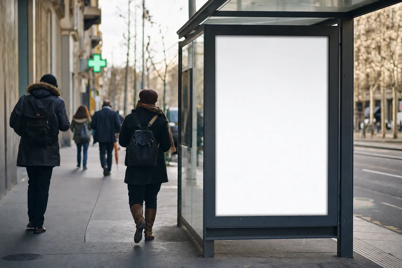 Panneau publicitaire urbain devant une rue commerçante, croix verte de pharmacie visible en arrière-plan.